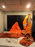 Orange insulated coveralls and orange gear with fishing lures spread on a table