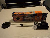 Full view of the metal detector with original box, showing the round search coil, telescoping shaft, and control unit.