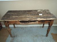 Front view of weathered pine table showing worn surface and drawer.