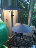 52-inch metal floor lamp and 19-inch metal table lamp both with conical metal shades and dark finish, floor lamp illuminated, placed by window.