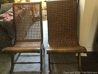 Front view of pair of cane chairs showing wooden frame and cane backs and seats with wear and damage.