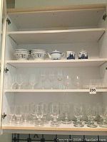 Upper cabinet shelf containing six handcrafted Italian bowls, teapot, lidded sugar bowl, and cream pitcher with blue patterns