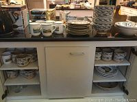 Image showing various dishes including cups, bowls, and plates from Tiffany & Co Bennett's Bridge pattern on countertop and cabinet shelves.