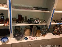 Photo of a shelf containing Native American bowl, stoneware pitchers, pewter bowl, stone vase, Asian figurines