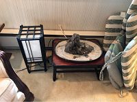 Photo showing the rice paper lamp, low wooden table, and Asian rock garden with sand and stones arranged on a ceramic tray