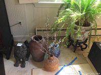Overview of all items: planter with fern on stand, metal lion, terracotta vase, basket vase, blue glazed vase