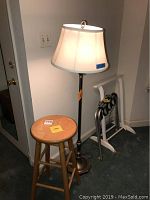 Wooden stool, floor lamp, luggage rack, and blanket rack grouped in a corner.