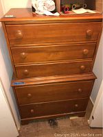 Full view of two piece wooden chest of drawers stacked, showing all drawers and wear on surfaces.