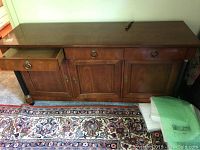Full view of Baker Furniture buffet showing three drawers and three cabinet doors with brass ring handles, with slight surface wear.