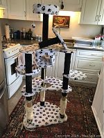 Front view of the full cat tower in kitchen environment showing the overall structure and paw print fabric.