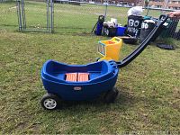 Photo showing blue Little Tikes plastic wagon with black pull handle on grass, visible signs of wear