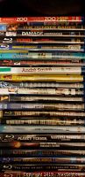 Stack of Blu-ray and DVD cases showing various movie titles including The Hunger Games, Damage, Town, Promised Land, The Wrestler, Windtalker, Planet Terror, and more.