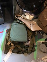 Pile of folded military gear including olive drab items, uniform fabric, and duffel bags