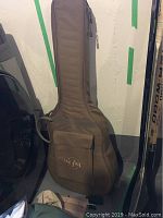 Brown Taylor padded gig bag standing against wall