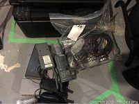 Photo of Sony PlayStation console with wired controllers, six game discs, two sets of walkie talkies, and a TI scientific calculator.