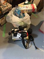Overview photo showing the BaByliss PRO Nano Titanium hair dryer, smaller travel hair dryer, bag with bath products, and heating pad box on a floor.