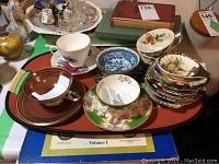 Overview photo showing multiple vintage teacups and saucers of various patterns including brown gold striped, floral, and blue white bowl.