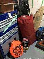 Overview showing red tent bag, orange seat pad, Coast light and other items