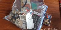Photo of plastic bag containing multiple Olympic pins, badges, and memorabilia