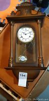 Full view of the Hermle pendulum wall clock showing wooden case and glass front with pendulum and clock face.