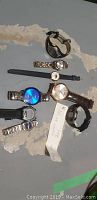 Eight watches laid out showing variety of straps and dials