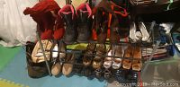 Wide shot of shoe rack holding multiple pairs of shoes including boots, heels, and flats, also showing belts and bags nearby.