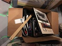 Box containing assorted sports memorabilia including framed photos, metal tins, and various items visible