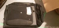 Front view of black Timbuk2 laptop messenger bag with flap closed, placed over a flat tablet device