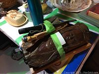 Wood carved bust with three knives on wooden tray with green tape