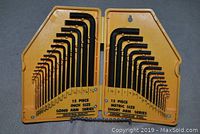 Opened yellow plastic foldable holder displaying 30 black hex keys, 15 metric short arm keys on right side and 15 inch size long arm keys on left side with sizes marked on holder.