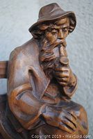 Close-up of the left side of the carved figure highlighting the pipe, hand, and detailed beard.