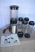 Full set of Cuisinart SmartPower blender with motor base, four BPA-free travel cups with lids, and two blade assemblies on a white surface with user manual.