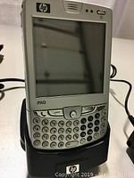 Front view of the HP iPAQ smartphone in the charging cradle showing keyboard and display.