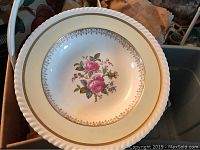 Close-up of a white ceramic bowl interior with pink rose floral design and gold trim.