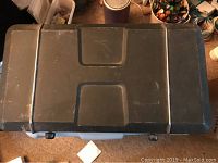 Top view of the closed portable camp stove showing the hinged lid with an indented handle area.