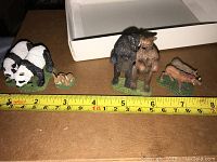 Full view of all animal figurines side by side with measuring tape showing scale