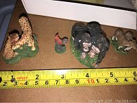 Top view showing cheetah, rooster, hen, gorilla family, and goat figurines with measuring tape for size reference.