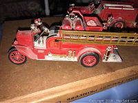 Side view of 1928 style die cast fire truck with mounted ladder and detailed fire equipment on the side.