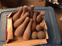 Wooden toy bowling pins and balls arranged inside an old box.