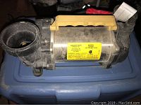 Photo showing the full view of the pond water pump with black plastic connections and a yellow handle on top.