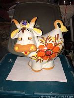 Photo of the cow-shaped ceramic cookie container showing front with floral paint details and closed eyes