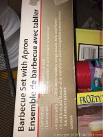 Photo of barbecue set box detailing the content: set includes 4 tools with stainless steel handles and a red apron