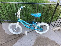 Full side view of the teal blue kids bike showing the frame, white tires, and patterned seat.