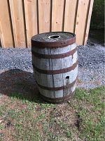 Full side view of antique wooden whiskey barrel showing weathered wood and rusted metal rings.