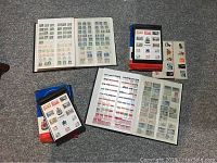 Overview of two stamp albums and two boxed Canada Centennial Issue stamp sets arranged on floor, showing stamp pages and packaging.