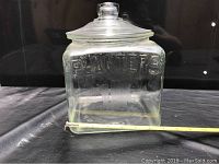 Front view of the vintage Planters glass jar showing the embossed "PLANTERS" lettering on the side, with a tape measure indicating size.