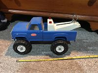 Side view of the blue vintage Tonka tow truck placed on carpet showing length approximately 15 inches with measuring tape.