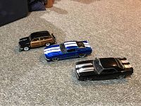 Photo of three diecast cars on carpet showing their sizes and colors: 1949 Woody Wagon, 1969 Camaro, 1967 Shelby GT500KR