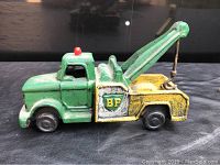 Side view of the green and yellow cast iron toy tow truck with BP logo on the door, showing wear and paint chipping.