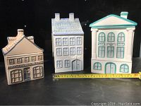 Front view of all three house-shaped ceramic canisters showing design details and size in inches with measurement tape.